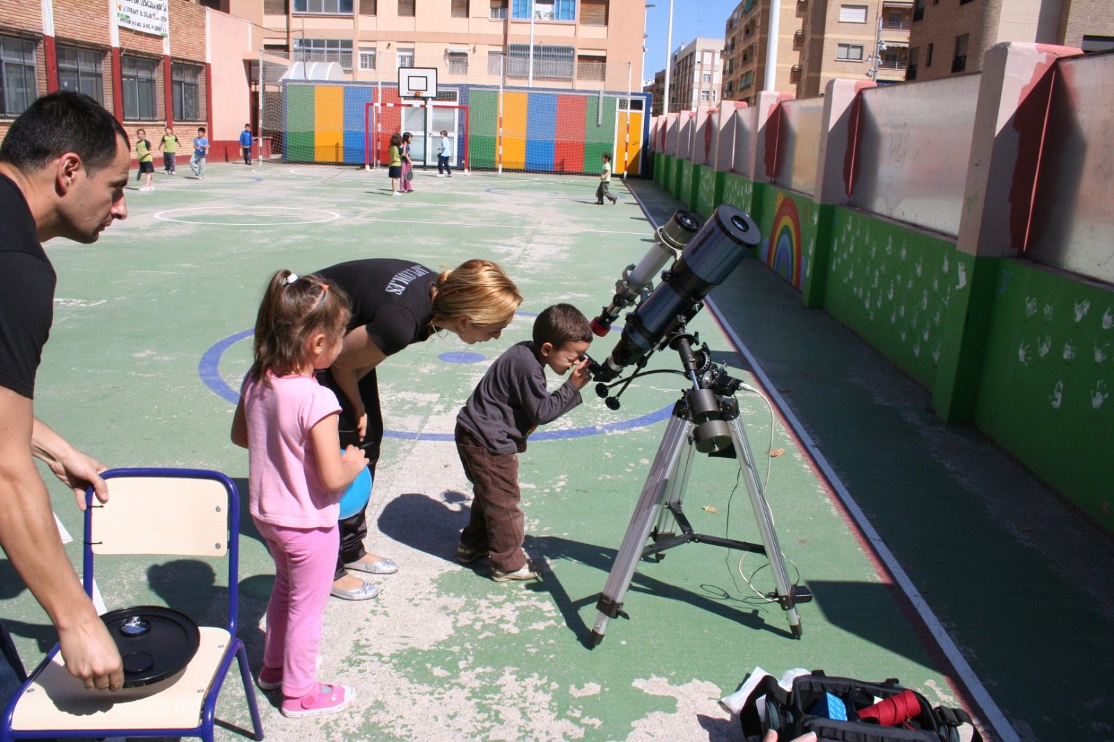 Niños observando por el telescopio en el patio del colegio